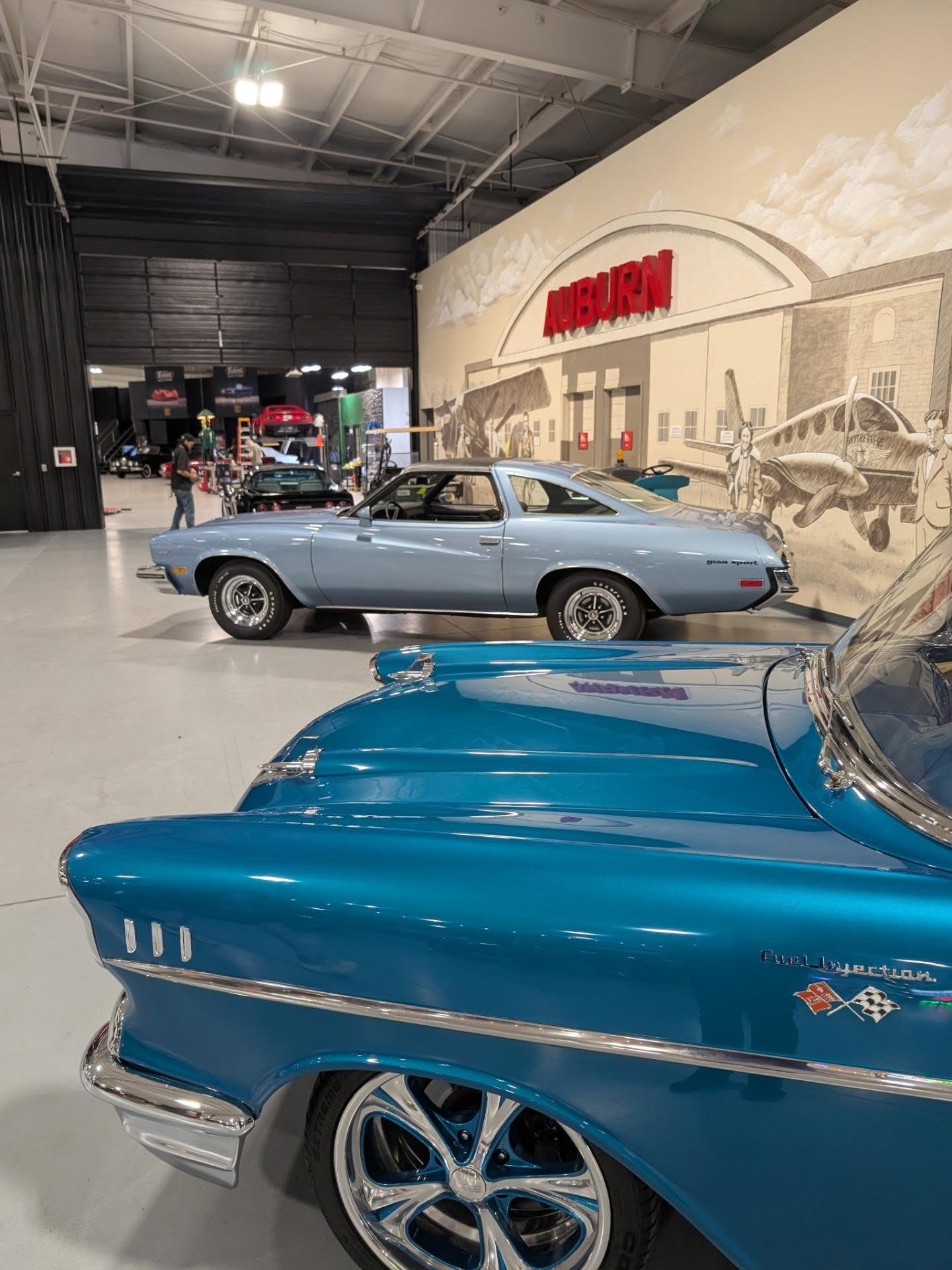 Classic cars beneath the Auburn mural inside the Auburn Classic Cars showroom