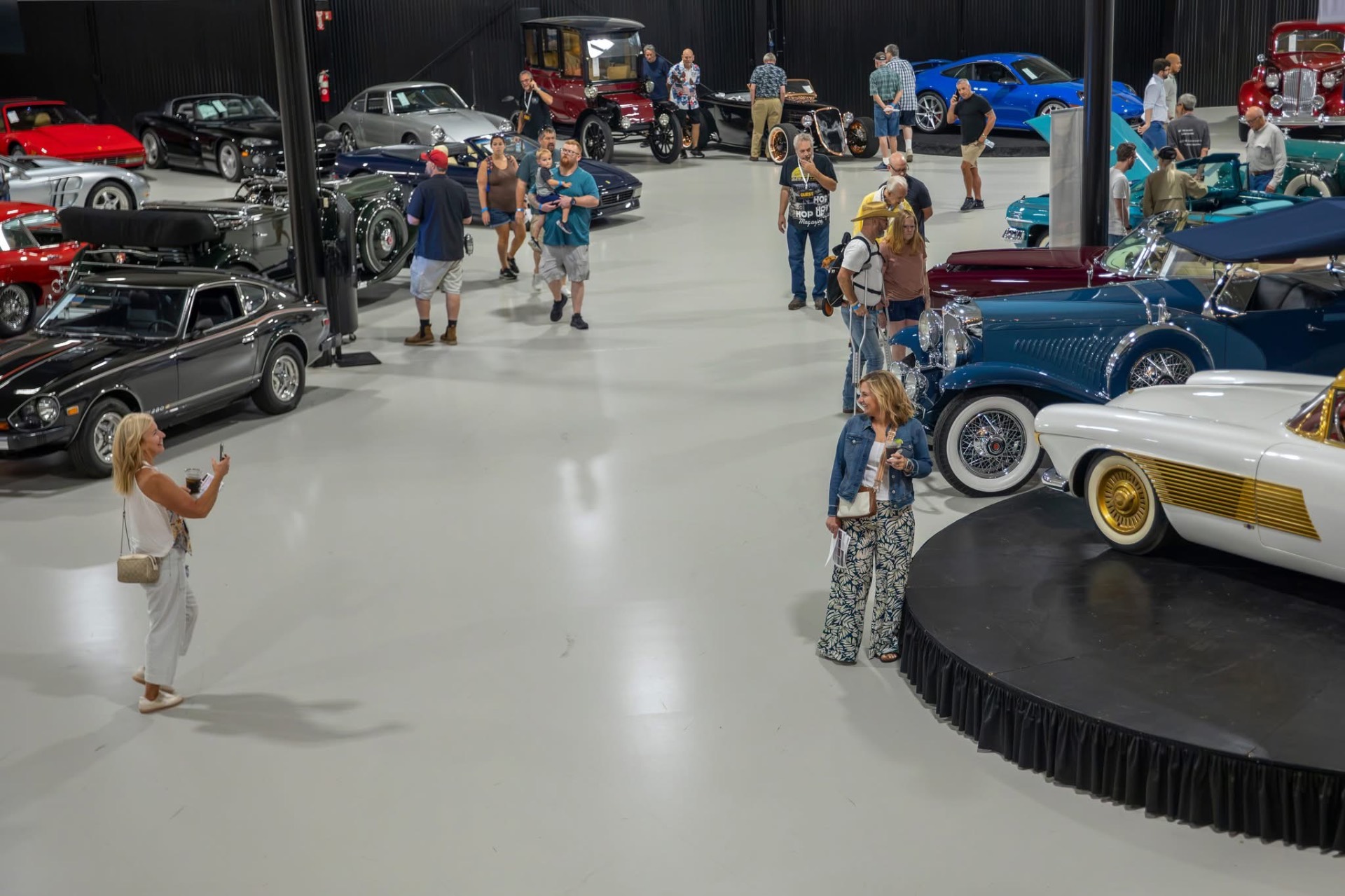Guests browsing collector cars at an Auburn Classic Cars showroom event